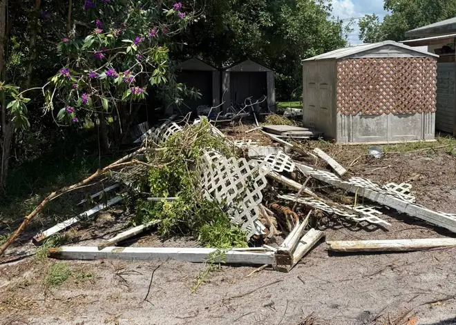 Pile of old fencing, lattice, and brush behind the house